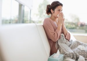 woman-sitting-on-couch-and-blowing-nose