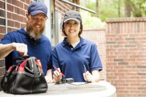 male-and-female-hvac-technicians-working-on-outside-condenser