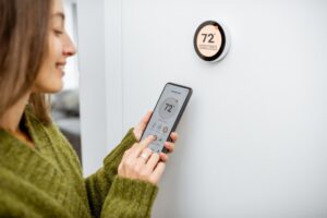person-adjusting-the-thermostat-using-an-app-on-their-phone